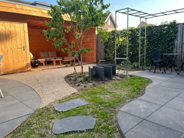 Tuin met grindbestrating, stapstenen en aangrenzend tegelpad.