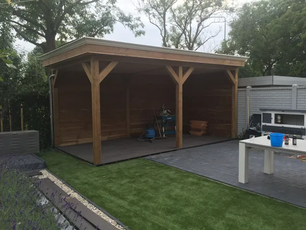 Houten overkapping met plat dak en cederhouten constructie naast lavendelborder.