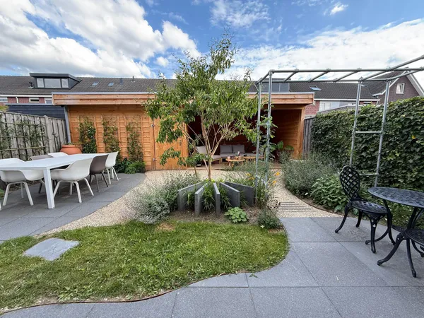 Houten overkapping met cederhouten gevel, pergola en tegelbestrating in achtertuin.