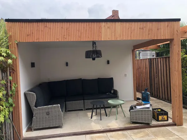 Moderne houten overkapping met cederhouten gevel, witte binnenwand en loungeset.