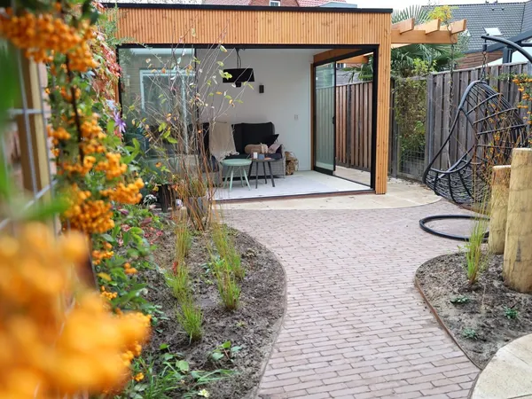 Moderne tuinkamer met glazen schuifwanden, cederhouten dak en klinkerpad.