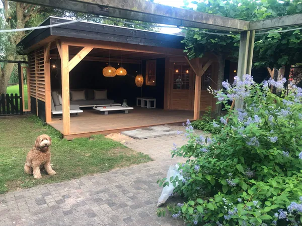 Houten overkapping met loungeset en sfeervolle hanglampen.