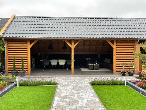 Houten overkapping met pannendak, eettafel en loungeset.