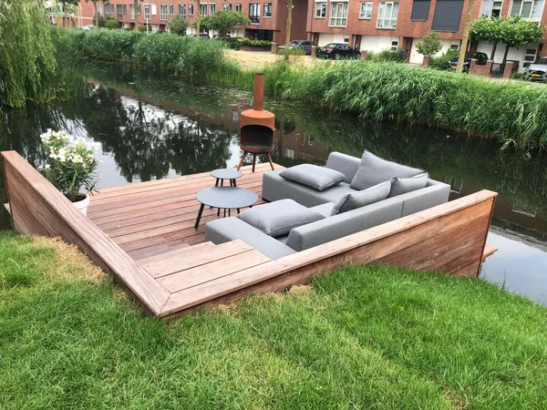 Houten vlonder met loungeset aan het water.