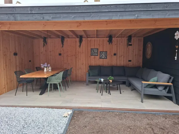 Houten overkapping met eettafel en loungeset onder cederhouten dak.