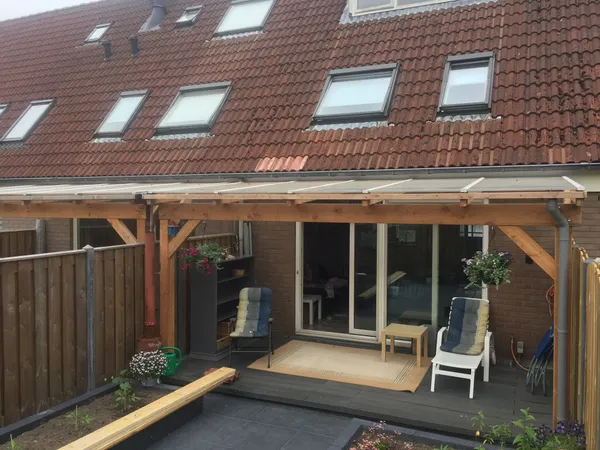 Houten veranda tegen woning met vlonder en bestrating.