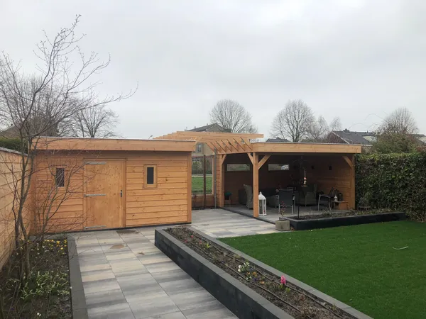 Houten overkapping met aangrenzende berging en strakke bestrating.
