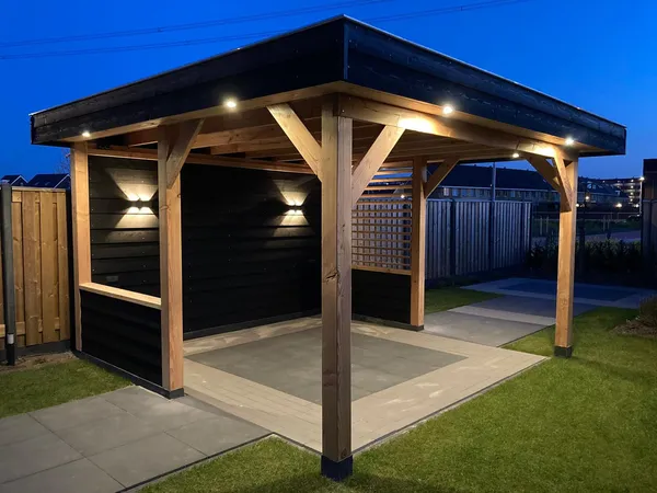 Houten overkapping met inbouwspots en zwart dak bij avondlicht.